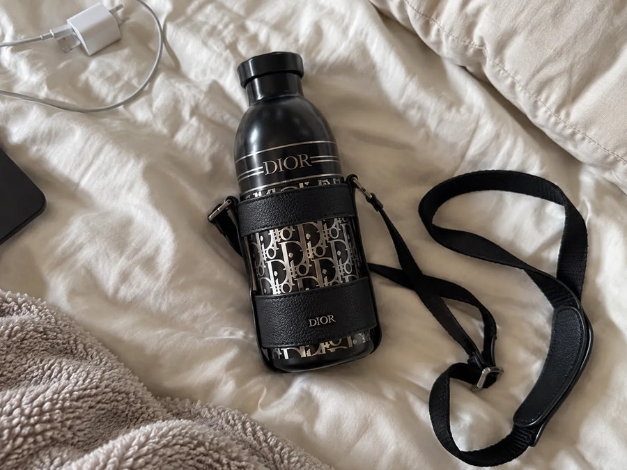Garrafa Dior Aqua preta sobre uma cama