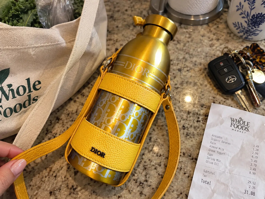 Garrafa Dior Aqua amarelo ouro sobre um balcao