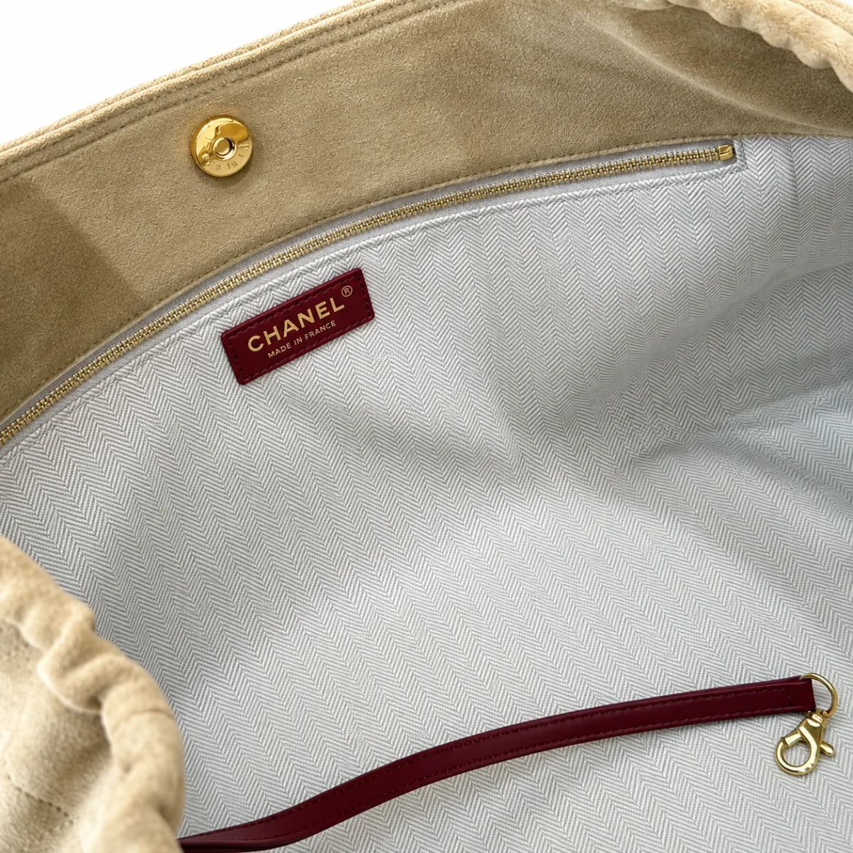 Inside view of beige quilted shoulder bag with herringbone lining